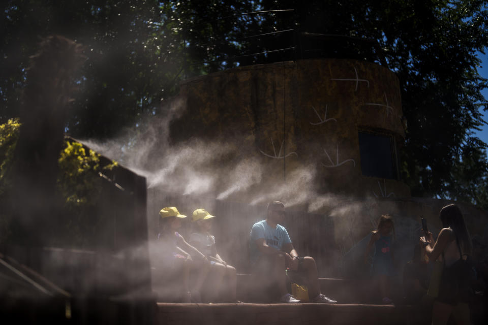 People cool off with water mist at at the Madrid Zoo, Spain, Thursday, July 13, 2023. Much of Spain was enjoying a brief respite Thursday from the suffocating temperatures of the second heatwave of the summer, which ended Wednesday. (AP Photo/Manu Fernandez)