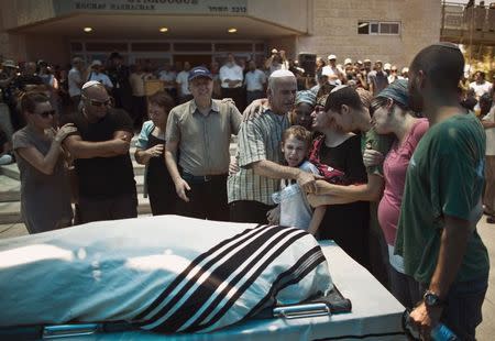 Family members mourn near the covered body of Malachi Rosenfeld during his funeral in the West Bank Jewish settlement of Kochav Hashachar July 1, 2015. REUTERS/Ronen Zvulun