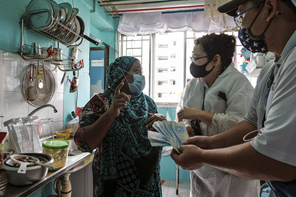 Keeping Hope Alive founder Fion Phua, second from right, and a volunteer holding supermarket vouchers talk to Sukkuriya Beevi, a 51-year old cleaner from India,Sunday, Oct. 4, 2020 in Singapore. Members of the volunteer group conduct weekend door-to-door visits to deliver goods or provide services to people in need. (AP Photo/Ee Ming Toh)