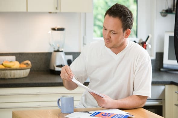 Man opening a letter in kitchen