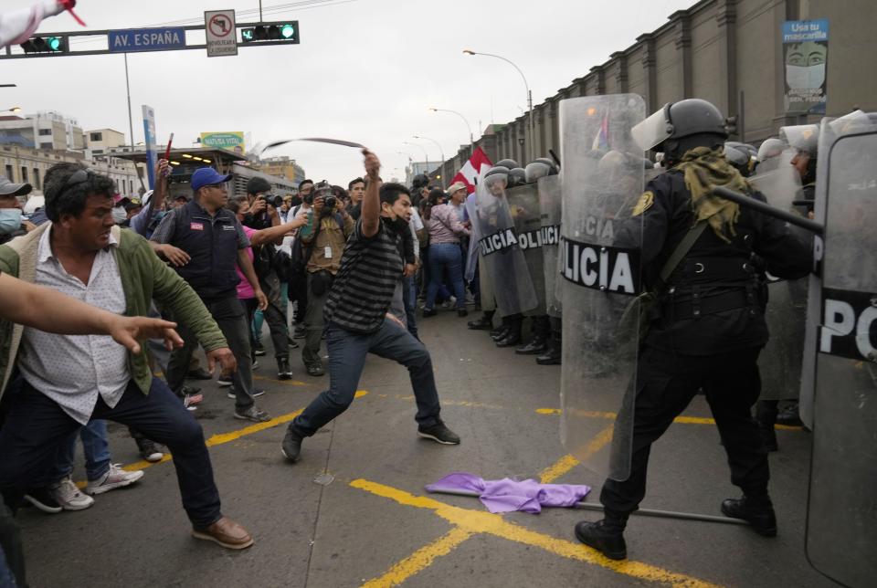 Supporters of former President Pedro Castillo confront riot police surrounding the police station where Castillo arrived earlier, in Lima, Peru, Wednesday, Dec. 7, 2022. Peru's Congress removed Castillo from office Wednesday, voting to replace him with the vice president, shortly after Castillo decreed the dissolution of the legislature ahead of a scheduled vote to oust him. (AP Photo/Martin Mejia)