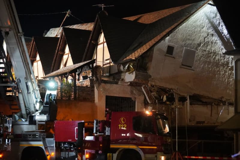 A fire department vehicle stands in front of a collapsed hotel. According to the latest information, nine people may be under the rubble and there is contact with some of them, the police announced on Wednesday night. Florian Blaes/dpa