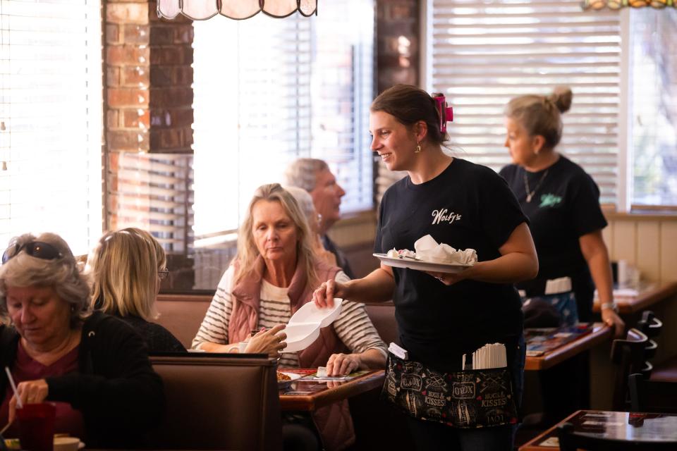 Server Taylor Stewart delivers a to-go container to customers at Wolfy's Restaurant on Jan. 30.