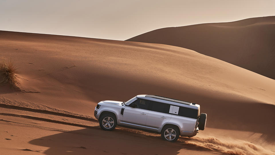 The 2023 Land Rover Defender 130 driving up a dune