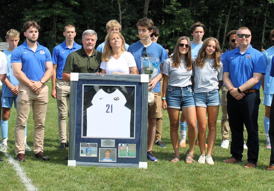 The Kenealy family consisting of dad Dan, mom Beth Jimmo and siblings Peter, Laura and Molly are surrounded by members of the York High School and Maine Maritime Academy soccer teams during Saturday's ceremony to retire Brian Kenealy's No. 21, the one he wore at MMA.