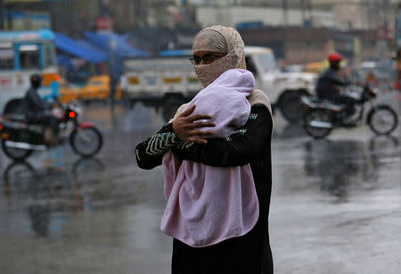 A woman covers her baby as she walks during heavy rains in Kolkata, India, May 3, 2019. REUTERS/Rupak De Chowdhuri