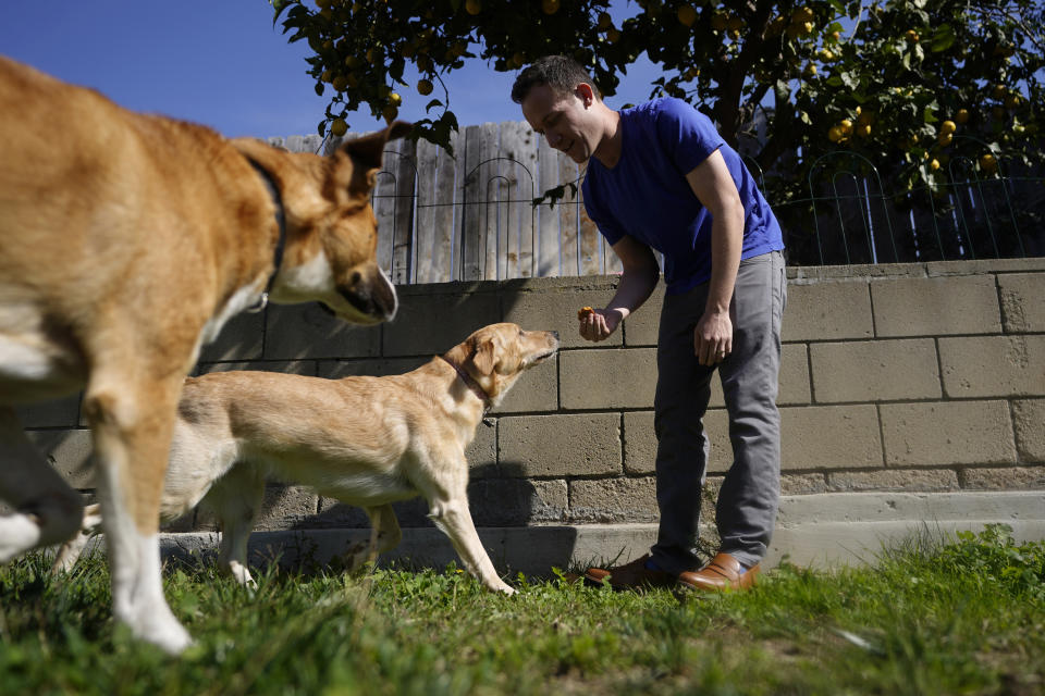 Alex Willen brings out treats for his dogs at his home, Thursday, Feb. 11, 2021, in San Diego. Willen was preparing to open a dog boarding business when the pandemic hit. Willen sensed the virus outbreak wouldn't end quickly, which meant dog owners wouldn't be traveling and many would keep working at home, eliminating the need for his services. He decided to restart a business he'd shelved in favor of boarding, dog treats. (AP Photo/Gregory Bull)