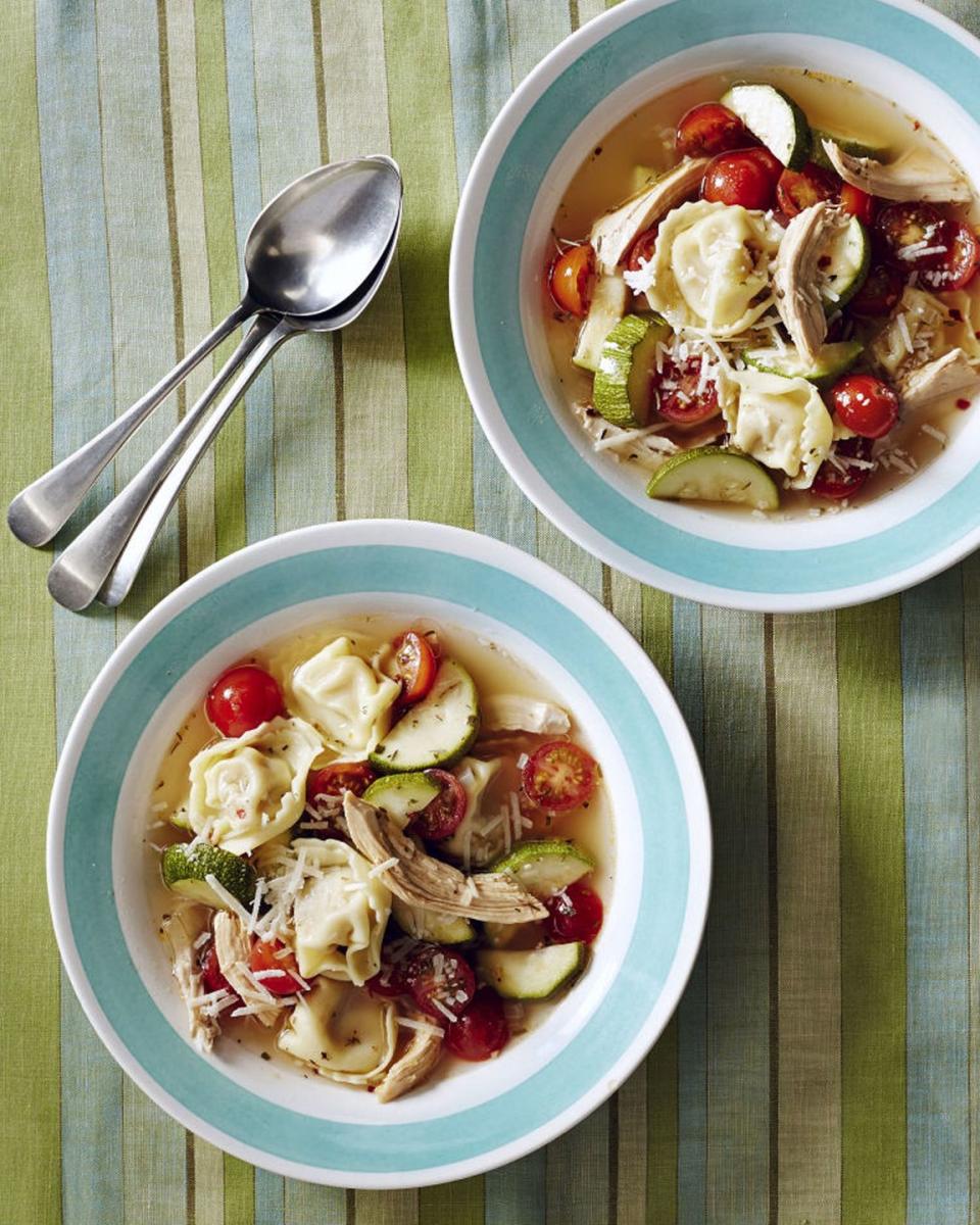 two bowls of chicken tortellini soup on a green striped tablecloth