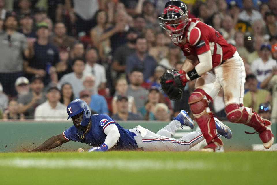 Texas Rangers' Adolis Garcia, left, scores on a throwing error by Boston Red Sox's Masataka Yoshida as Red Sox's Connor Wong, right, chases the ball during the fifth inning of a baseball game Thursday, July 6, 2023, in Boston. (AP Photo/Steven Senne)