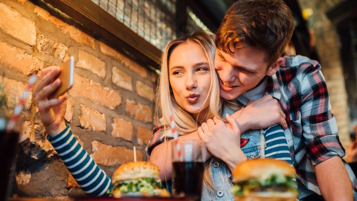 young couple making a selfie while having lunch at the pub