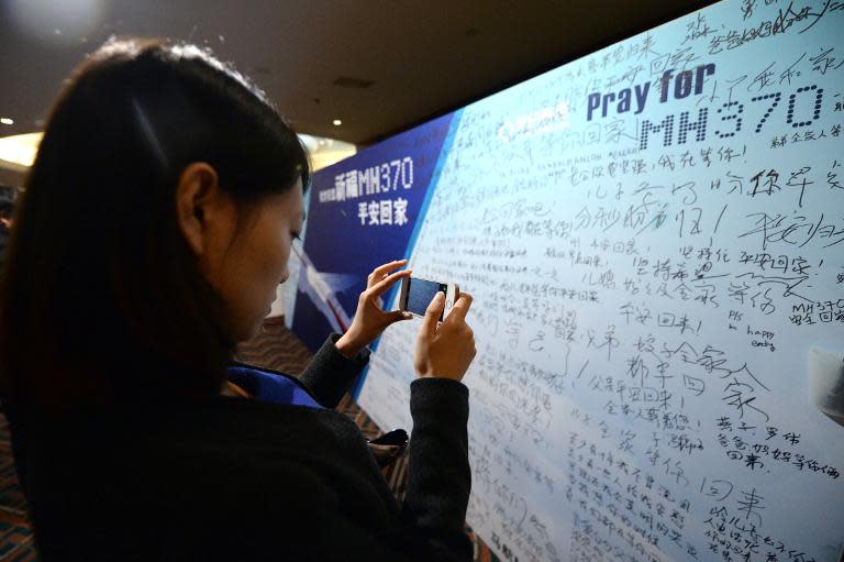 A Chinese woman takes a photo of a message board set up by relatives of passengers from the missing Malaysia Airlines flight MH370 at Metro Park Lido Hotel in Beijing, on March 24, 2014