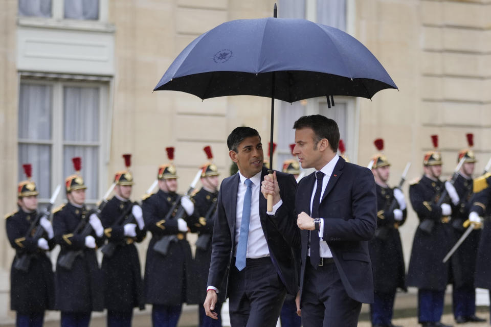 French President Emmanuel Macron, centre right, uses an umbrella to protect Britain's Prime Minister Rishi Sunak after a French-British summit at the Elysee Palace in Paris, Friday, March 10, 2023. French President Emmanuel Macron and British Prime Minister Rishi Sunak meet Friday in Paris in a summit aimed at mending relations following post-Brexit tensions, improving military and business ties and toughening efforts against Channel migrant crossings. (AP Photo/Kin Cheung, Pool)