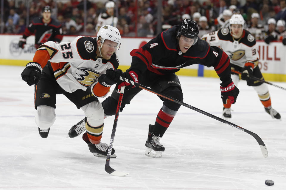 Anaheim Ducks right wing Ondrej Kase (25), of the Czech Republic, and Carolina Hurricanes defenseman Haydn Fleury (4) chase the puck during the third period of an NHL hockey game in Raleigh, N.C., Friday, Jan. 17, 2020. Anaheim won 2-1 in overtime. (AP Photo/Gerry Broome)