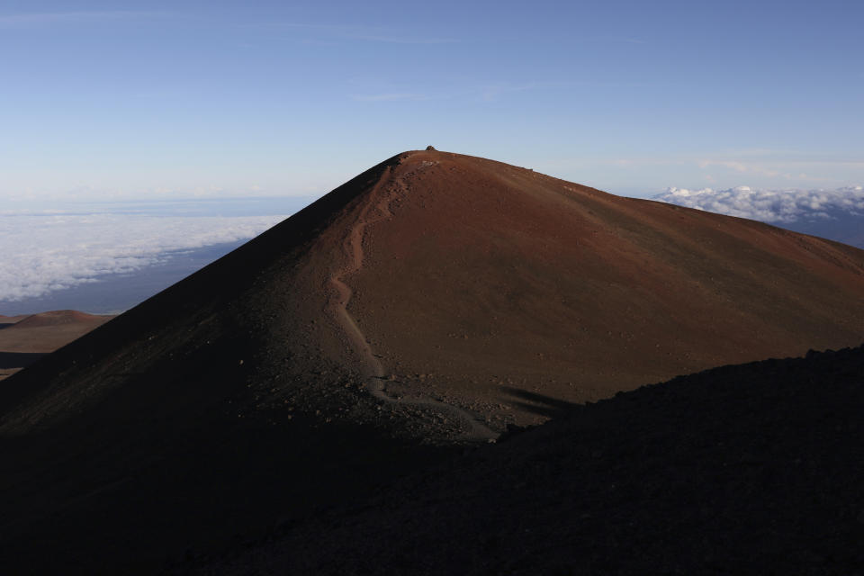 The summit of Hawaii's Mauna Kea is shown on Sunday, July 14, 2019. Hundreds of demonstrators are gathered at the base of Hawaii's tallest mountain to protest the construction of a giant telescope on land that some Native Hawaiians consider sacred. State and local officials will try to close the road to the summit of Mauna Kea Monday morning to allow trucks carrying construction equipment to make their way to the top. Officials say anyone breaking the law will be prosecuted. Protestors have blocked the roadway during previous attempts to begin construction and have been arrested. (AP Photo/Caleb Jones)