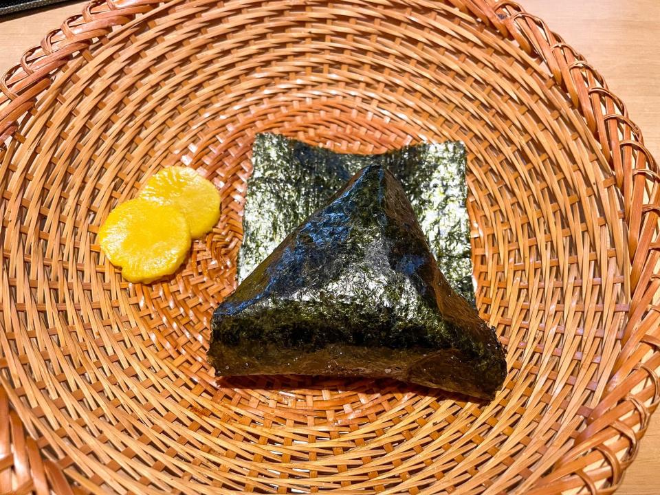 An onigiri and pickled radish in a basket.