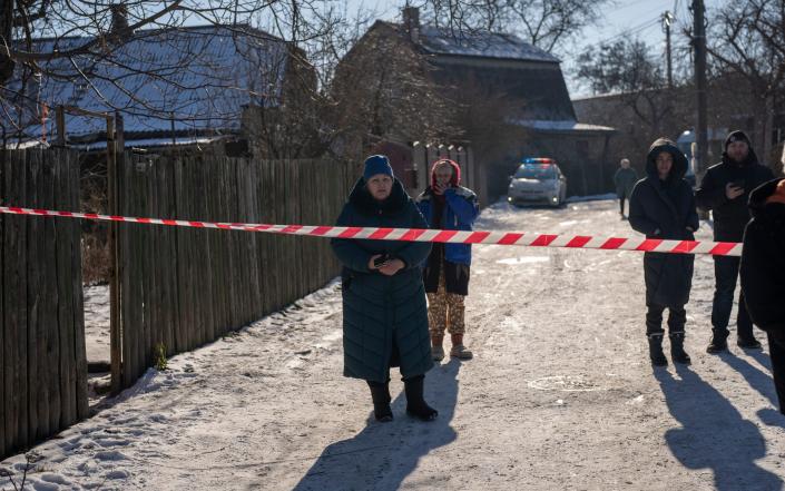 Residents wait behind police cordon to return to their homes after a rocket attack in Kyiv suburbs - AP