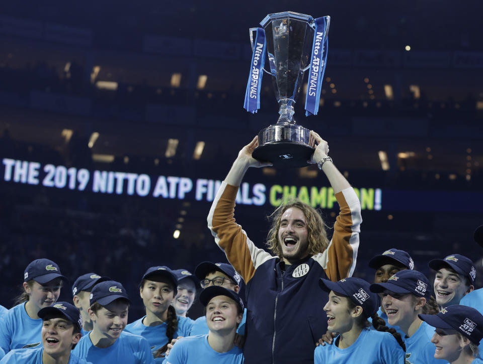 Stefanos Tsitsipas of Greece holds up the trophy and celebrates with the ball kids after defeating Austria's Dominic Thiem in the final of the ATP World Finals tennis match at the O2 arena in London, Sunday, Nov. 17, 2019.(AP Photo/Kirsty Wigglesworth)