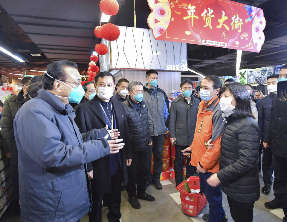 In this photo released by China's Xinhua News Agency, Chinese Premier Li Keqiang, left, speaks with people at a supermarket in Wuhan in central China's Hubei province, Monday, Jan. 27, 2020. China on Monday expanded its sweeping efforts to contain a deadly virus, extending the Lunar New Year holiday to keep the public at home and avoid spreading infection. (Li Tao/Xinhua via AP)