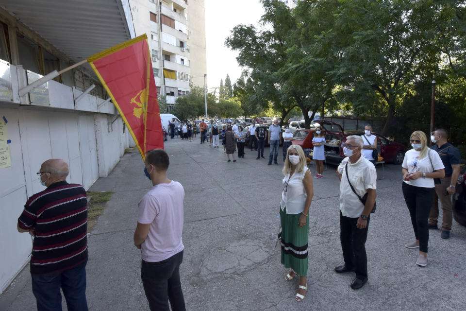 People wait in line at a poling station in Podgorica, Montenegro, Sunday, Aug. 30, 2020. Voters in Montenegro on Sunday cast ballots in a tense election that is pitting the long-ruling pro-Western party against the opposition seeking closer ties with Serbia and Russia. The parliamentary vote is marked by a dispute over a law on religious rights that is staunchly opposed by the influential Serbian Orthodox Church. (AP Photo/Risto Bozovic)
