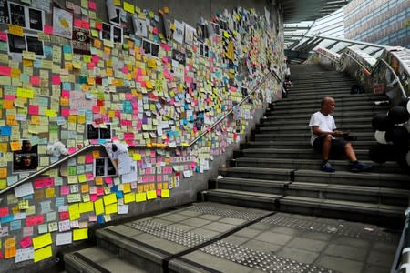 A man sits on the stairs of the Legislative Council as he reads post-it notes left behind by protesters, a day after they broke into the building, in Hong Kong