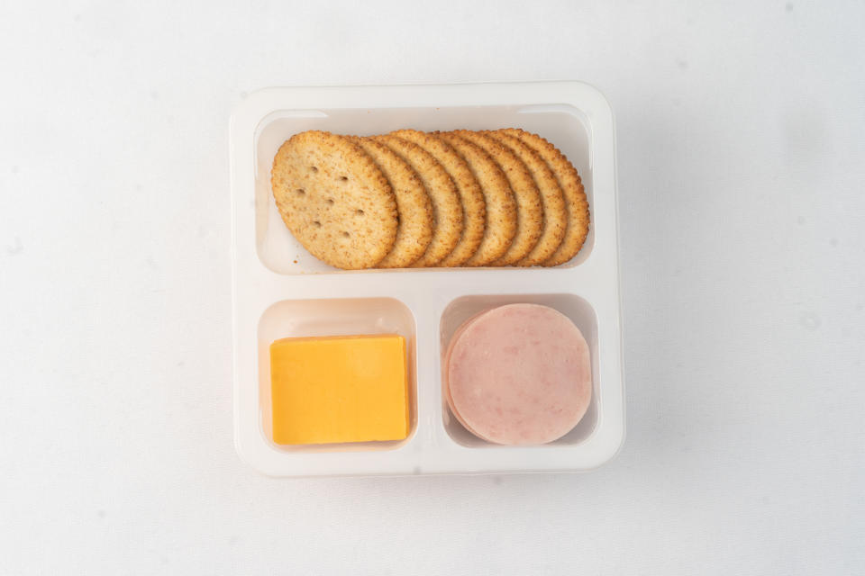 Crackers, cheese slice, and a portion of deli meat served on a white tray