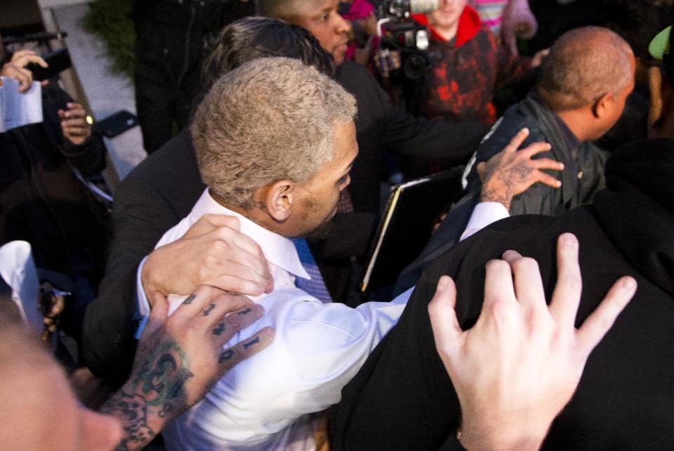 Singer Chris Brown is surrounded by bodyguards as he departs the H. Carl Moultriel courthouse Monday, Oct. 28, 2013, in Washington. A charge against the Grammy Award-winning R&B singer has been reduced to a misdemeanor and he was ordered released after his arrest Sunday following an altercation outside a Washington hotel. (AP Photo/ Evan Vucci)