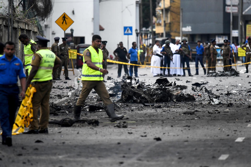 Sri Lankan security personnel inspect the debris of a car after it explodes near St. Anthony's Shrine on Sunday. Source: Getty