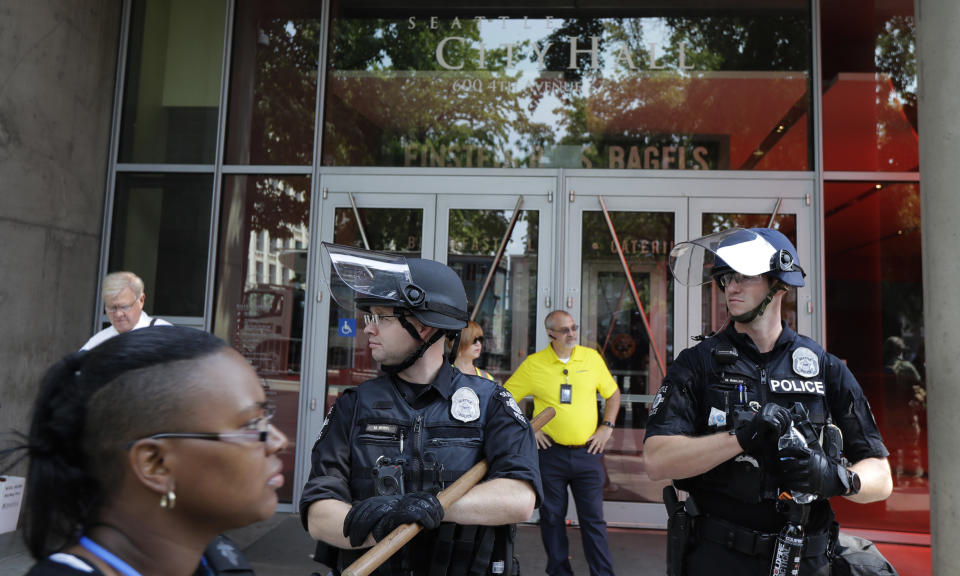 Seattle Police officers in helmets stand watch in front of City Hall in Seattle before a rally held by members of Patriot Prayer and other groups advocating for gun rights, Saturday, Aug. 18, 2018, at City Hall in Seattle. (AP Photo/Ted S. Warren)