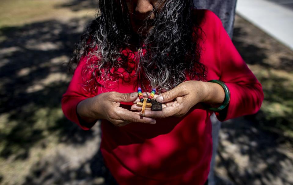 Bertha Valdez sostiene la cruz de su collar afuera de su casa