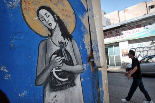 A man walks by graffiti related to the economic crisis on a wall in Athens. Eurogroup chief Jean-Claude Juncker warned a radical left victory in Greece would have "unpredictable" consequences for the eurozone as Greeks fed up with austerity prepared for Sunday's elections