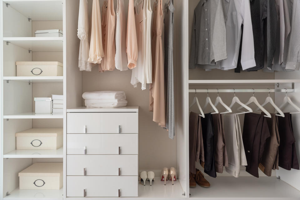 modern closet with clothes hanging on rail, white wooden wardrobe, interior design concept