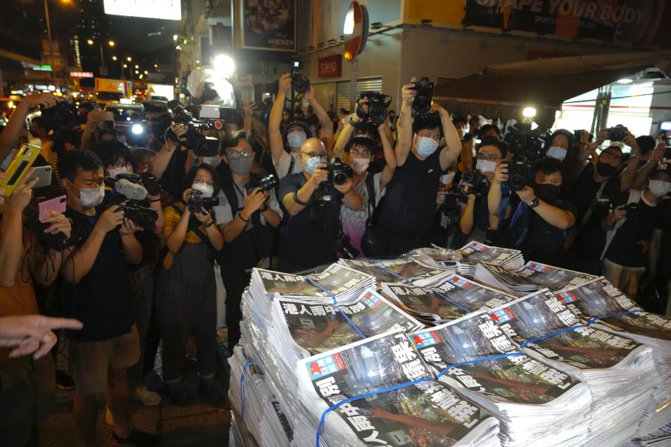 FILE - Members of the media take photos of stacks of the last issue of Apple Daily as they arrive at a newspaper booth in Hong Kong, June 24, 2021. (AP Photo/Vincent Yu, File)