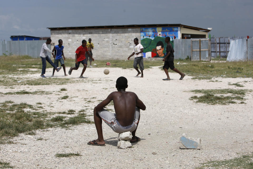 In this May 17, 2012 photo, a youth watches others play soccer in the Cite Soleil shantytown at the site where a stadium may be built in Port-au-Prince, Haiti. A local sports hero, a New York real estate developer and a well-known architect are teaming up to build a soccer stadium here, hoping to revive the seaside shantytown. The organizers also hope the stadium, scheduled to break ground within six months and due to be built by the end of 2013, will bring an initial 500 jobs and inject commerce into the shanty city, where politicians to pay residents to fight their battles as proxy forces. (AP Photo/Dieu Nalio Chery)