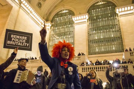 An activist shouts as she leads dozens of protesters, who hold placards with the names of some 150 people who they said were "killed or brutalized" by the police, during a demonstration against police brutality in New York City's Grand Central Terminal on January 5, 2015. REUTERS/Elizabeth Shafiroff