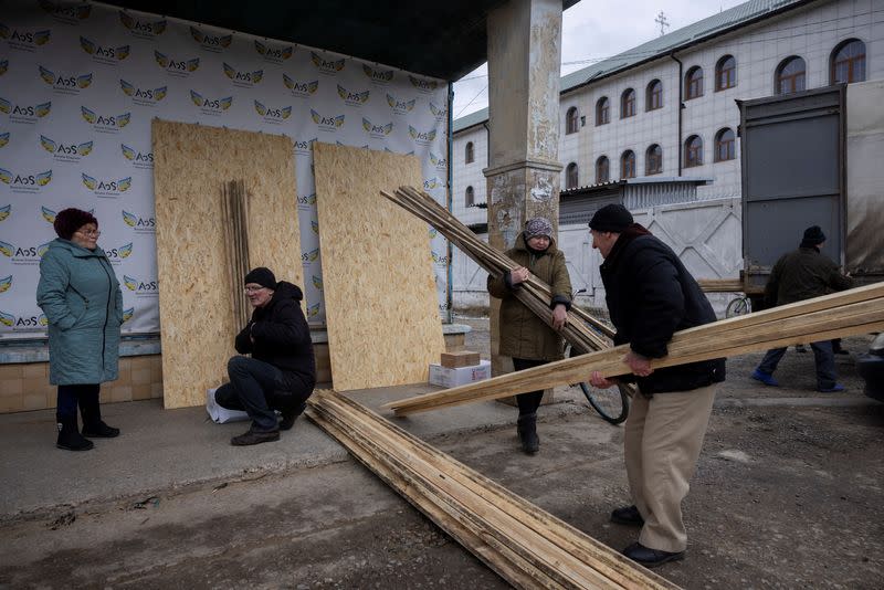 People pick up donated building material to patch up their houses that were destroyed as a result of missile strikes in Kurakhove near Avdiivka