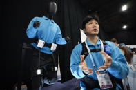The H-Flex robotic system is displayed behind Junyoung Moon of Hurotics during CES Unveiled before the start of the CES tech show Sunday, Jan. 7, 2024, in Las Vegas. The H-Flex robotic system is designed to help users with rehabilitation. (AP Photo/Ryan Sun)