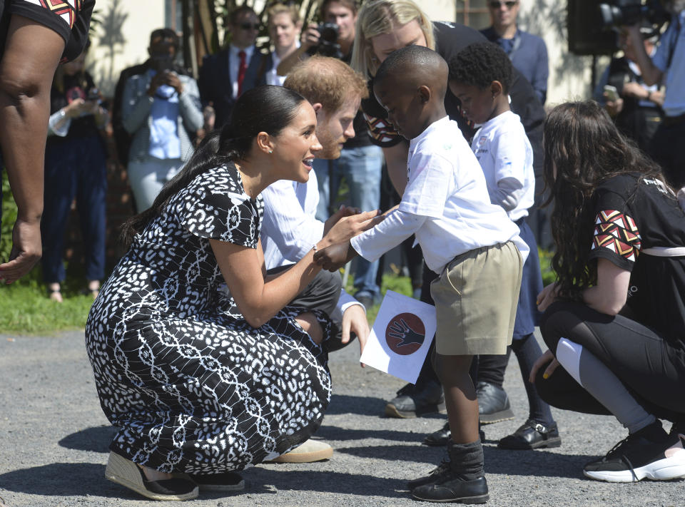 Britain's royal couple Prince Harry and Meghan Duchess of Sussex, greet children on their arrival at the Nyanga Methodist Church in Cape Town, South Africa, Monday, Sept, 23, 2019, which houses a project where children are taught about their rights, self-awareness and safety, and are provided self-defence classes and female empowerment training to young girls in the community. The royal couple are starting their first official tour as a family with their infant son, Archie (Courtney Africa / Africa News Agency via AP, Pool)