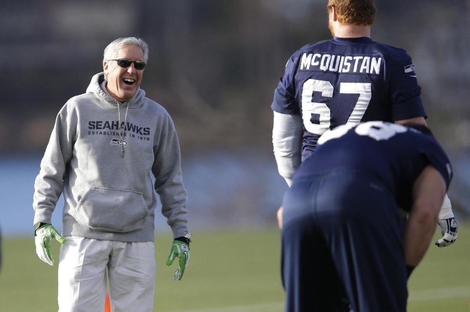 Seattle Seahawks coach Pete Carroll, left, laughs as he stands near tackle Paul McQuistan (67) during stretching drills before NFL football practice, Friday, Jan. 3, 2014, in Renton, Wash. Seattle plays at home in a playoff game on Jan. 11. (AP Photo/Ted S. Warren)