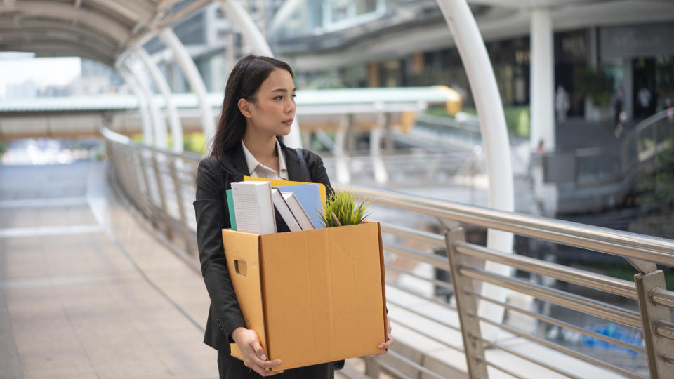 Businesswoman leaving office with box of personal items