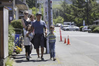 In this Thursday, May 28, 2020, photo, tourists Tuan Nguyen and his wife, Sarah Nguyen, walk with their children, twins Lukas and Lauren, 7, and Alyssa, 4, as they walk through downtown in Cannon Beach, Ore. The Nguyens were visiting from the Portland, Ore., suburbs but elected to stay in their RV instead of a hotel to feel safer from the coronavirus. (AP Photo/Gillian Flaccus)