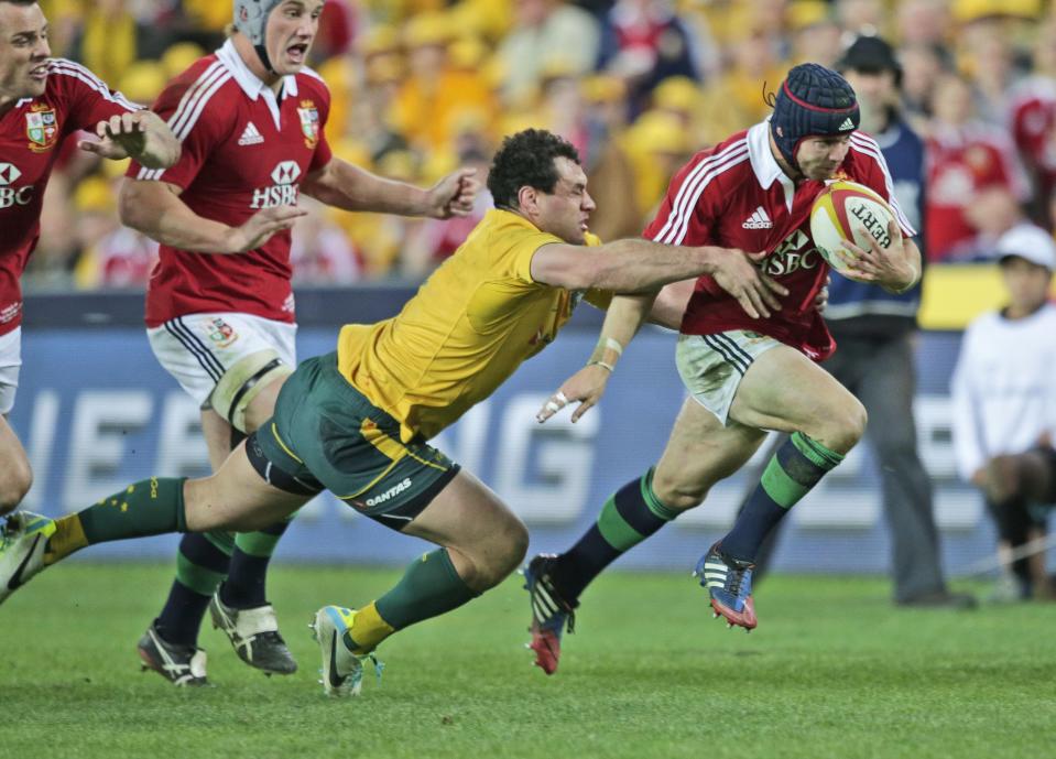 FILE - British and Irish Lions' Leigh Halfpenny, right, makes a break as Australia's George Smith dives for him during the third rugby test match in Sydney, Australia, on July 6, 2013. The Rugby World Cup will take place to the backdrop of a concussion lawsuit that has similarities to one settled by the NFL in 2013 at a likely cost of more than $1 billion. (AP Photo/Rob Griffith, File)