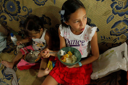 Juliani Caceres, grand daughter of Carmen Penaloza, have rice and platain for lunch at her home in San Cristobal, Venezuela April 5, 2018. REUTERS/Carlos Eduardo Ramirez/Files