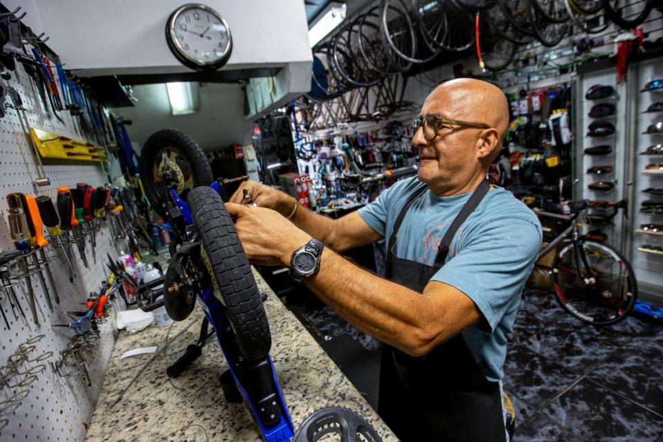 El propietario de la tienda, William Andrés Arias Serrano, de 60 años, realiza reparaciones menores sin cargo para un cliente en Willie’s Bicycles en el vecindario Upper East Side de Miami, el martes 10 de mayo de 2022. El cliente pagó a pesar del gesto.