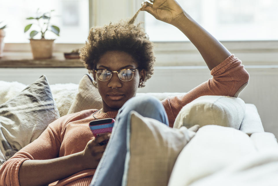 A woman is sitting on a couch and looking at her phone