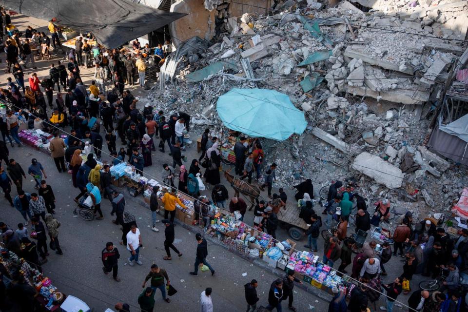 PHOTO: Palestinians buy food at a local market next to a destroyed residential building by the Israeli airstrikes, during the Muslim holy month of Ramadan, in Rafah, Gaza Strip, March 14, 2024.  (Fatima Shbair/AP)