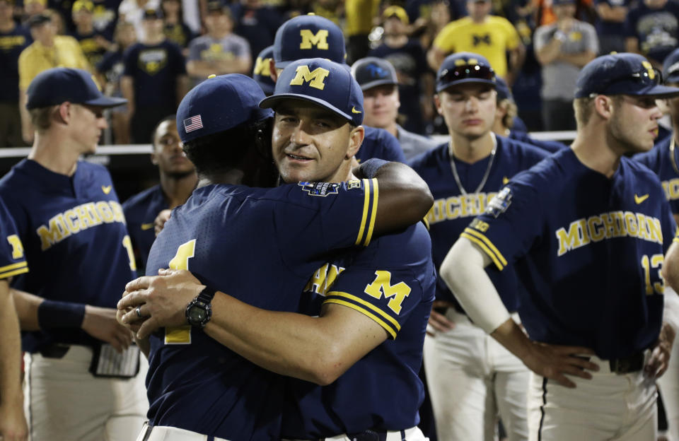 FILE - In this June 26, 2019, file photo, Michigan coach Erik Bakich, center, is hugged by Michigan's Ako Thomas (4) as they watch Vanderbilt celebrate after Vanderbilt defeated Michigan to win Game 3 of the NCAA College World Series baseball finals in Omaha, Neb. As disappointing as it's been to have the college baseball season shut down because of the coronavirus pandemic, Michigan coach Erik Bakich sees a silver lining. "I do think the coming years will be the deepest college baseball has ever been," he said. (AP Photo/Nati Harnik, File)