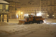 A clearing vehicle clears the snow in the city centre in the early hours of the morning on Sunday, Feb. 7, 2021 in Wernigerode, Germany. Deep Tristan has caused huge amounts of snow in the Harz mountains, like here in Wernigerode. (Matthias Bein/dpa via AP)