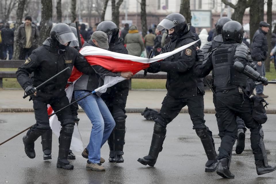 Belarus police detain a protester with an opposition flag during an opposition rally in Minsk, Belarus, Saturday, March 25, 2017. A cordon of club-wielding police blocked the demonstrators' movement along Minsk's main avenue near the Academy of Science. Hulking police detention trucks were deployed in the city center. (AP Photo/Sergei Grits)