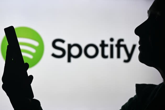 An image of a woman holding a cell phone in front of a Spotify logo displayed on a computer screen, on April 29, 2024, in Edmonton, Canada.  - Credit: Artur Widak/NurPhoto/Getty Images