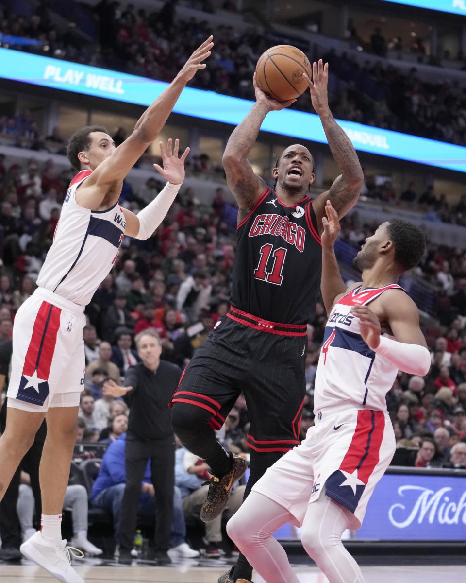 Chicago Bulls' DeMar DeRozan (11) drives to the basket between Washington Wizards' Patrick Baldwin Jr., left, and Jared Butler during the second half of an NBA basketball game Monday, March 25, 2024, in Chicago. The Wizards won 107-105. (AP Photo/Charles Rex Arbogast)